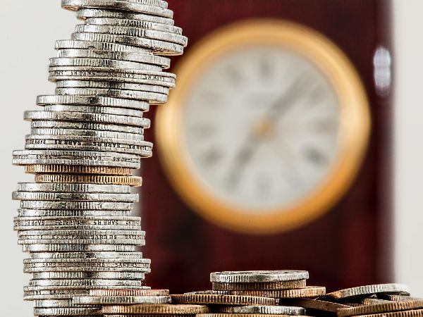 Stack of coins in front of a clock