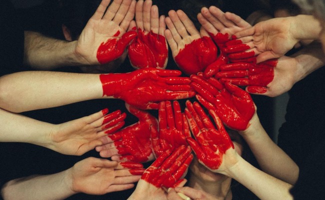 Red heart painted on a collection of people's hands