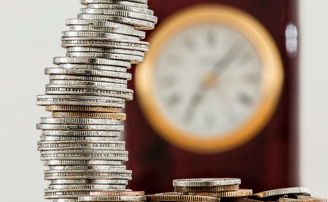 Stack of coins in front of clock