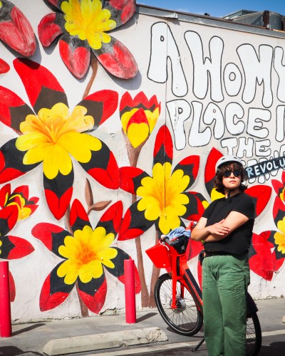 Electro-bici riders stop in front of a mural in Pacoima